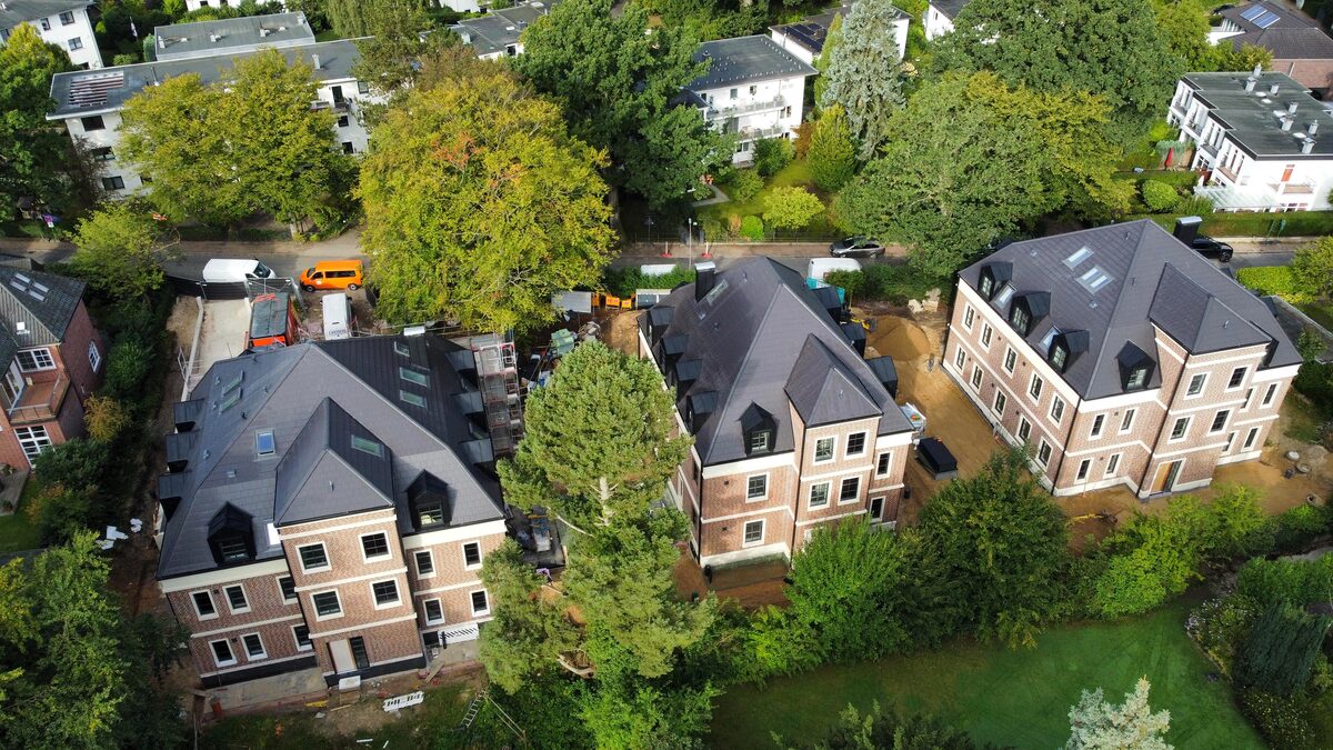 Luftbild vom Oktober 2026: die drei Villen nebeneinander am Zickzackweg zwischen alten Bäumen